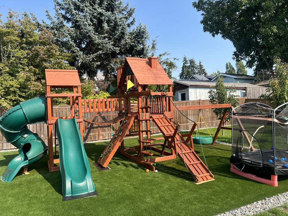 Wooden backyard playset with green slides and swings