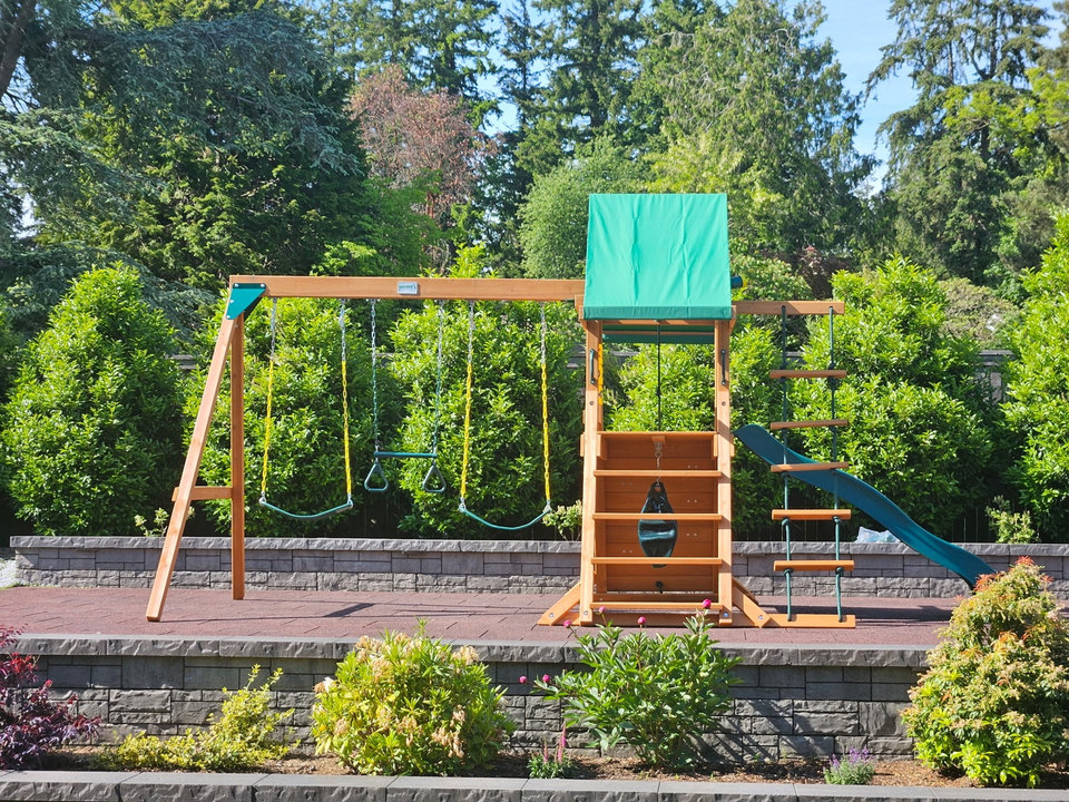 Wooden playset with swings beside a landscaped garden