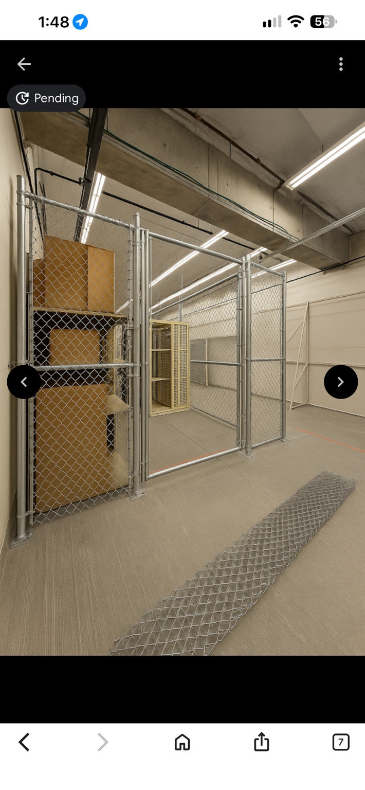Indoor chain-link enclosure and gate with work materials visible